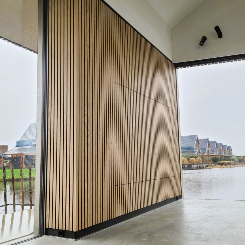 Muur van latten en akoestisch vilt met verborgen televisie in villa aan het water